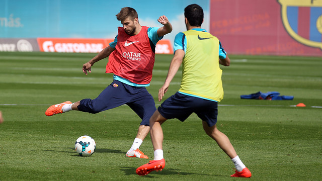 Gerard Piqué en una acció de l'entrenament amb Busquets d'esquenes